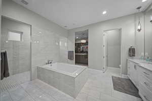 Bathroom featuring vanity, walk in shower, a garden tub, a walk in closet, and light marble finish floors