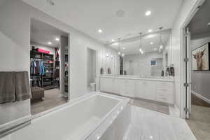 Full bath featuring a spacious closet, double vanity, and a garden tub