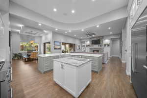 Kitchen with open floor plan, gray cabinets, premium appliances, a stone fireplace, and recessed lighting