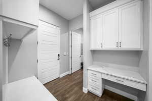 Unfurnished office featuring built in desk and dark wood-style floors