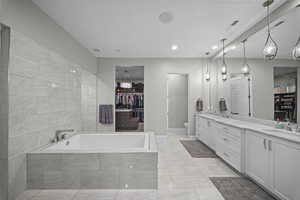 Bathroom featuring a walk in closet, double vanity, a garden tub, and recessed lighting