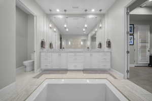 Full bath with double vanity, recessed lighting, and a bathtub
