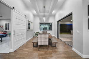 Dining space featuring a tray ceiling, a barn door, and wood finished floors
