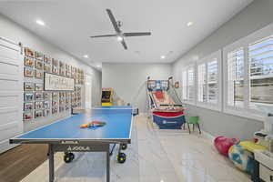 Rec room with ceiling fan, recessed lighting, light marble finish floors, and a barn door