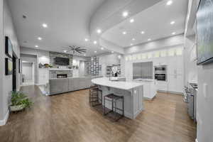 Kitchen featuring a breakfast bar area, white cabinetry, ceiling fan, recessed lighting, and light stone countertops