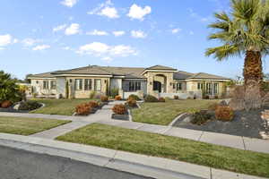 View of front of home featuring stone siding, a front lawn, stucco siding, and a tile roof
