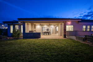 Rear view of property with ceiling fan, stucco siding, a patio, and stone siding