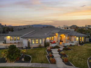 View of front of house featuring stone siding, a lawn, stucco siding, and a tiled roof