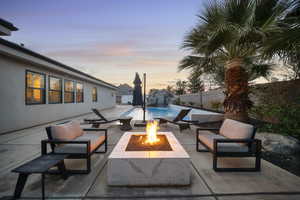 Patio terrace at dusk with a patio area, a fenced backyard, and a fire pit