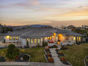 Back of property with stone siding, a lawn, stucco siding, and a tile roof