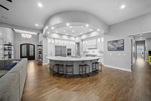 Kitchen with glass insert cabinets, open floor plan, white cabinets, dark wood-type flooring, and recessed lighting