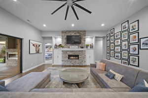 Living area with a fireplace, a ceiling fan, recessed lighting, and wood finished floors