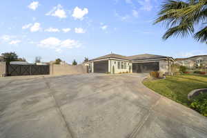 Prairie-style home with a gate, an attached garage, driveway, and stucco siding