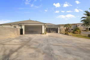 View of property exterior with stucco siding, driveway, a tile roof, and a garage