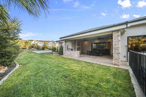 Back of property with stucco siding, ceiling fan, a patio area, and a yard