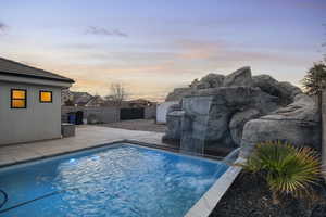 Pool at dusk with a patio area and a fenced backyard