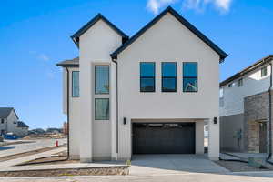 Contemporary house with an attached garage, concrete driveway, stucco siding, and brick siding