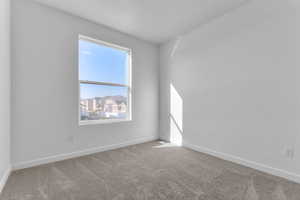 Carpeted spare room featuring baseboards