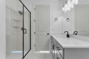 Bathroom featuring vanity, a stall shower, and light marble finish floors