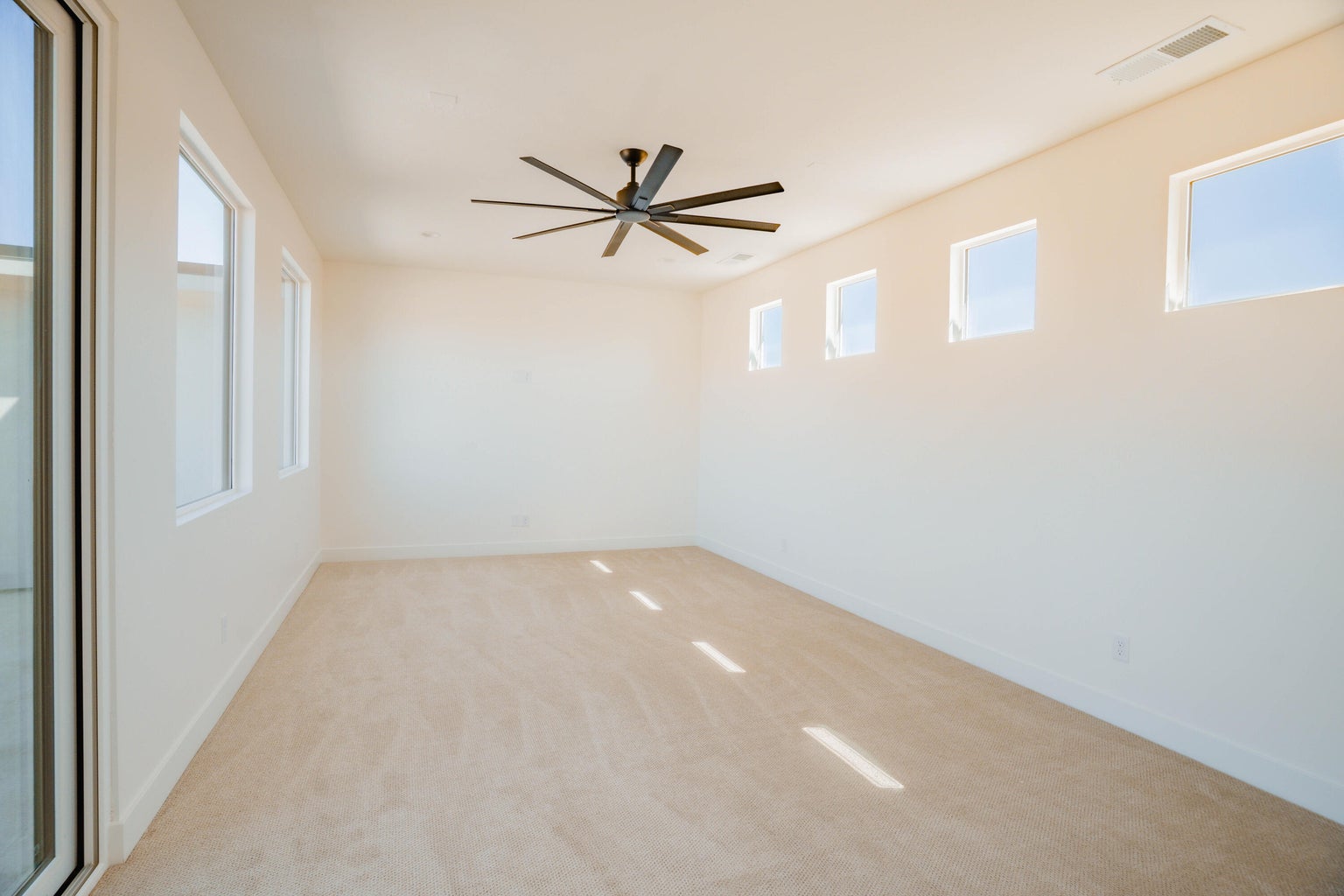 Empty room featuring light carpet and ceiling fan