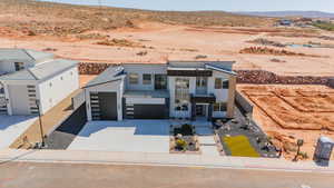 Contemporary house with stucco siding, a desert view, concrete driveway, a mountain view, and a view of countryside
