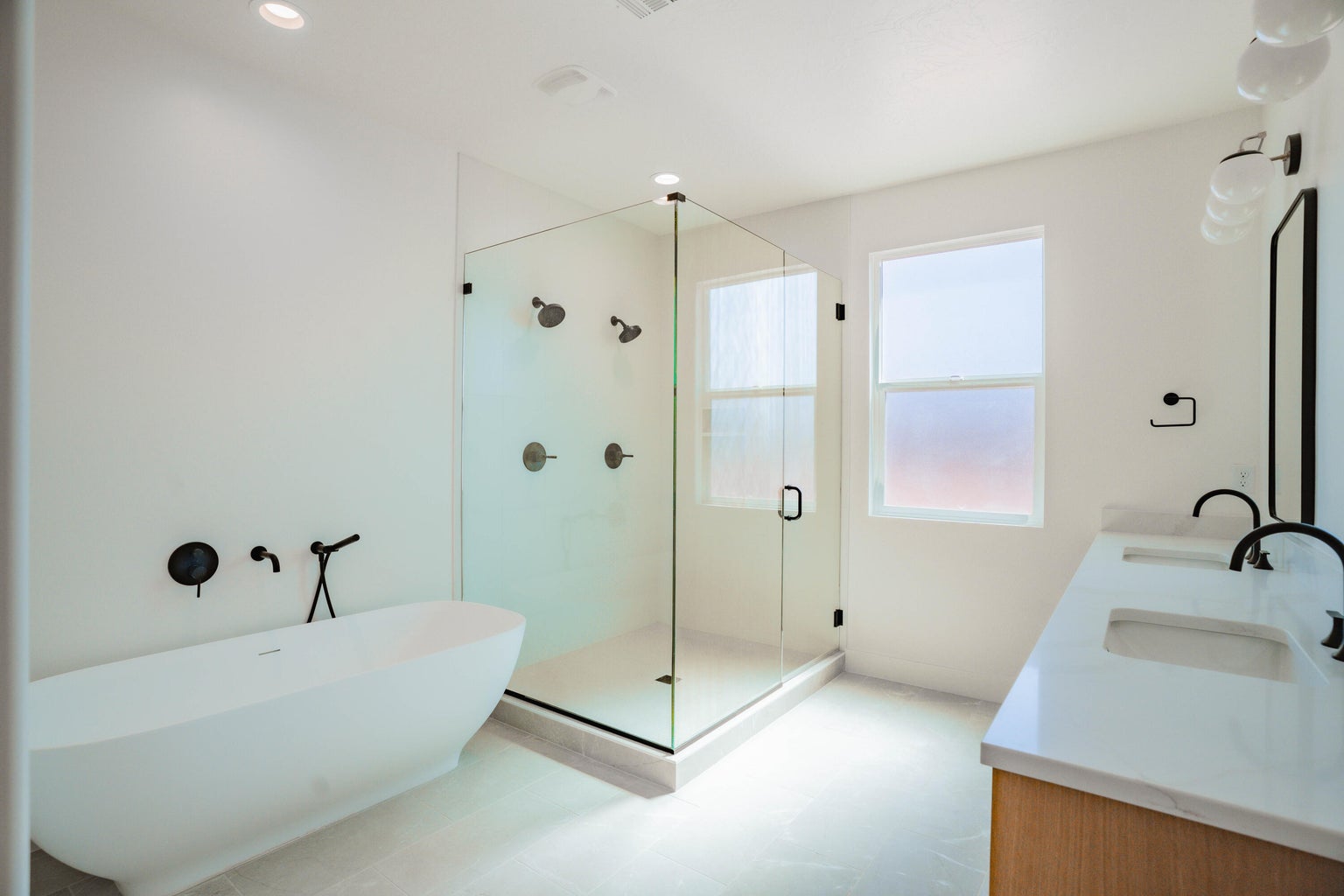 Bathroom with a freestanding tub, double vanity, a stall shower, recessed lighting, and light flooring