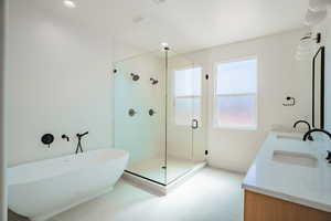 Bathroom with a freestanding tub, double vanity, a stall shower, recessed lighting, and light flooring