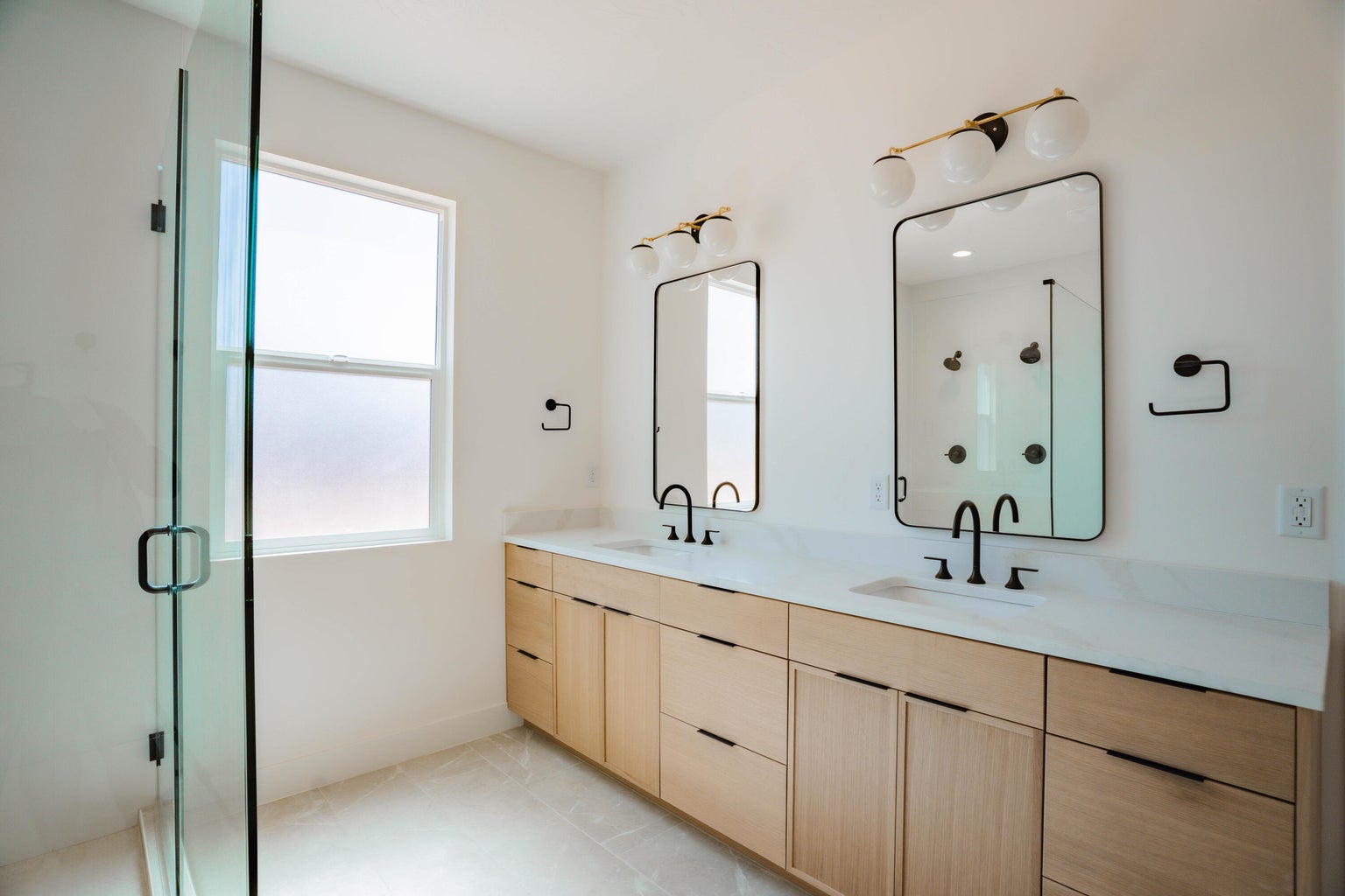 Full bath with a shower stall, double vanity, and light tile patterned floors