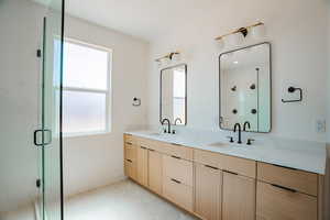 Full bath with a shower stall, double vanity, and light tile patterned floors