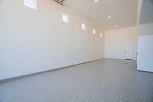 Unfurnished room featuring a towering ceiling and speckle patterned floor