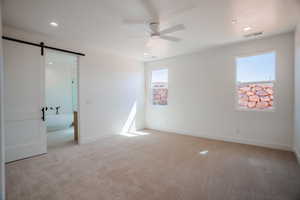 Unfurnished bedroom featuring a barn door, light carpet, ceiling fan, and recessed lighting