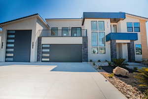 Contemporary home featuring stone siding, concrete driveway, and stucco siding