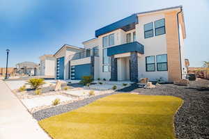 Contemporary home with stone siding, stucco siding, a garage, driveway, and a balcony