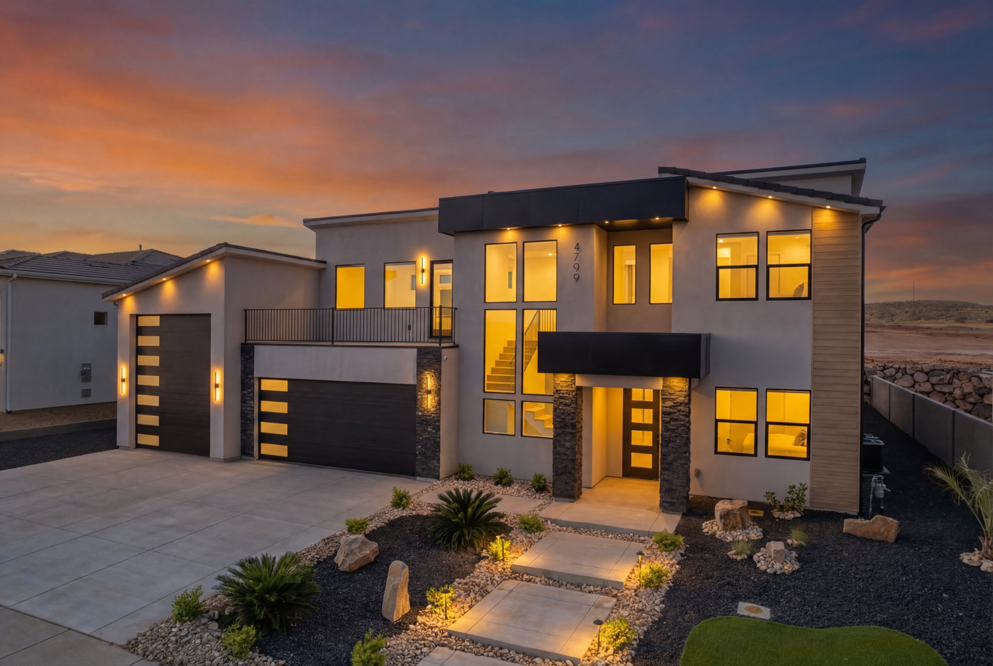 Modern architectural exterior with a stucco finish, stone accents, and a sloped roofline