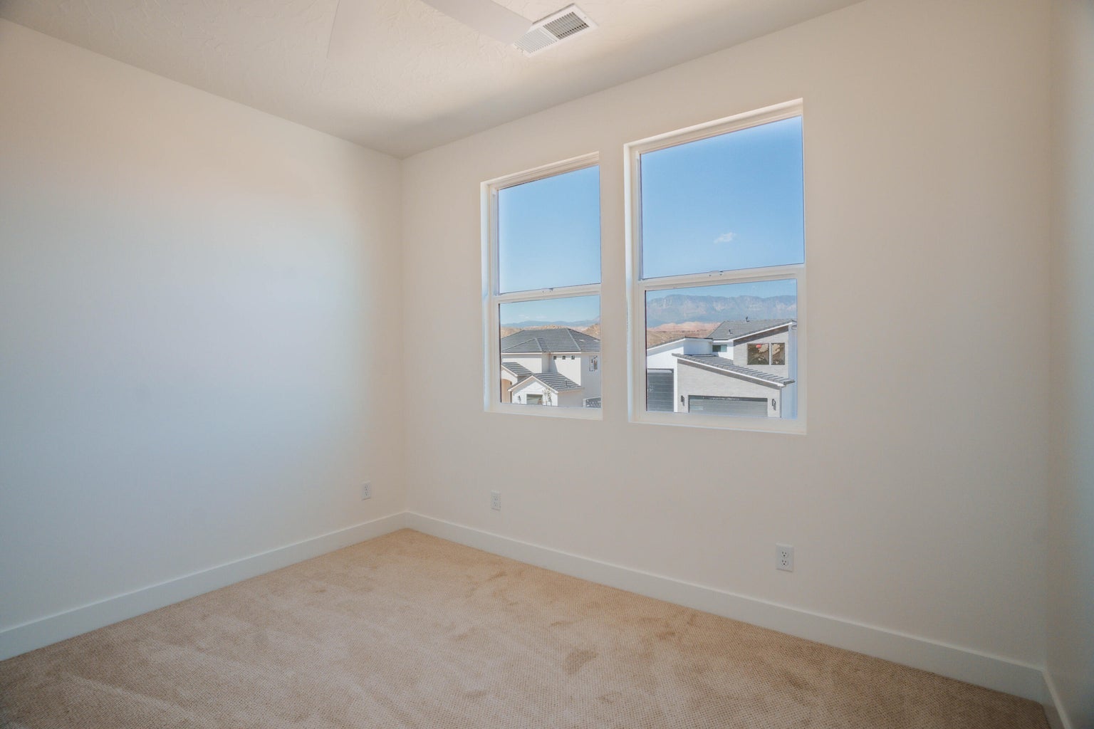 Carpeted spare room featuring baseboards and a ceiling fan