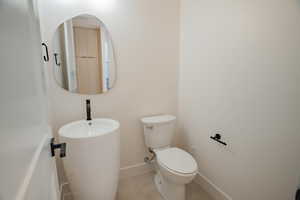 Half bathroom featuring toilet and tile patterned flooring