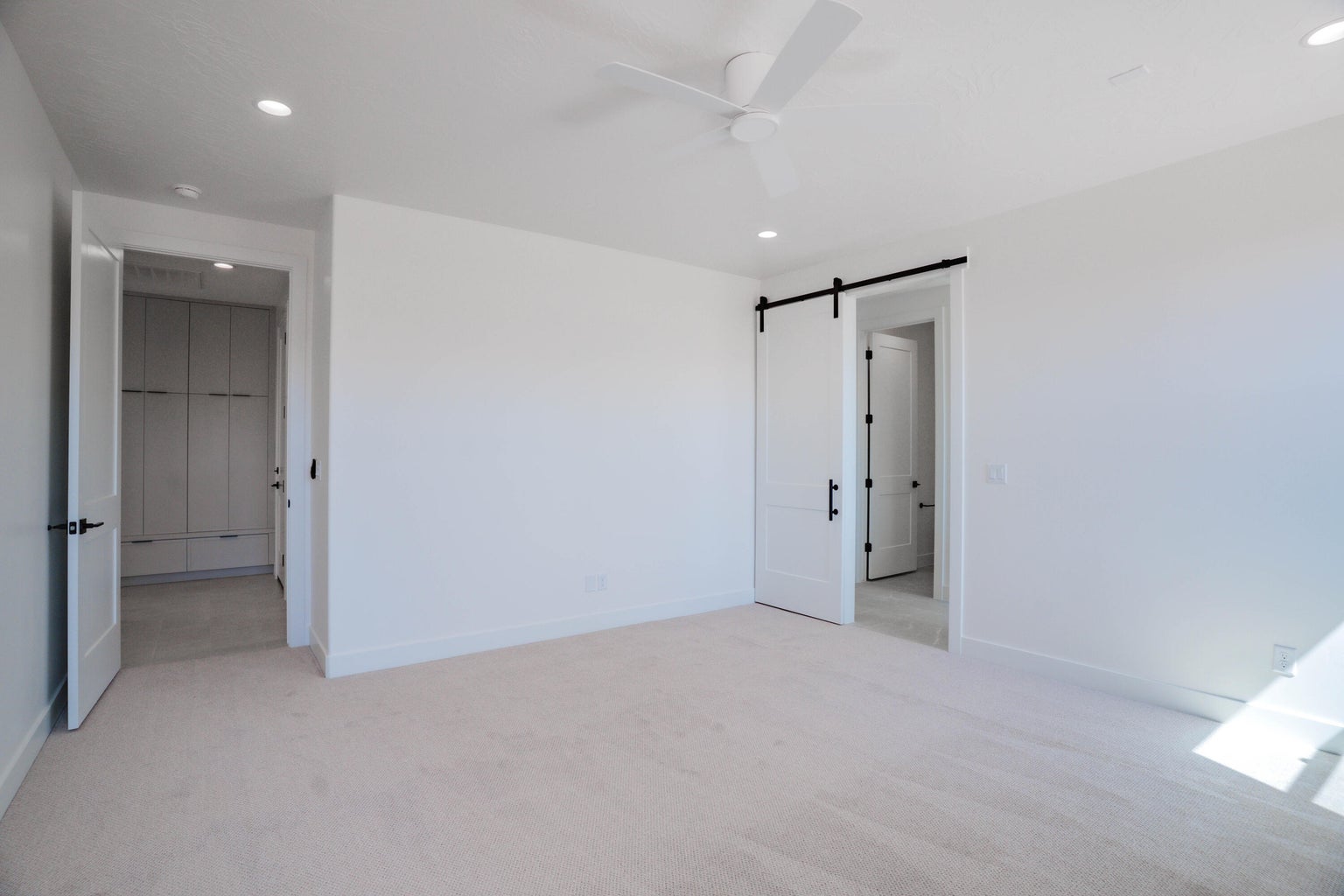 Unfurnished bedroom featuring a barn door, light carpet, recessed lighting, and a ceiling fan
