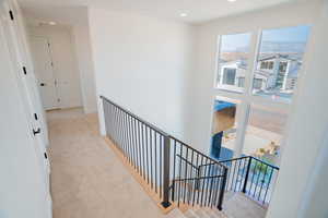 Hall with light carpet, an upstairs landing, and recessed lighting