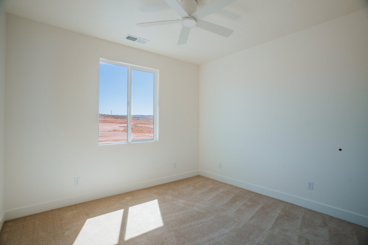 Carpeted empty room with baseboards and a ceiling fan