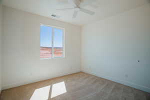 Carpeted empty room with baseboards and a ceiling fan