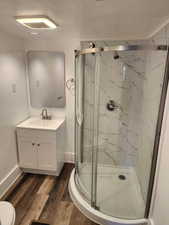 Bathroom with vanity, dark wood-style flooring, and a marble finish shower
