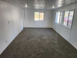 Unfurnished room with dark carpet and a textured ceiling