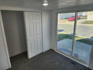 Doorway featuring a textured ceiling and carpet flooring