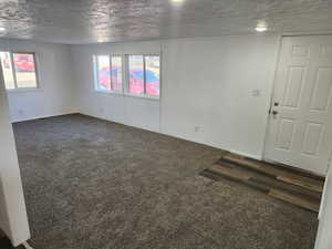 Unfurnished room featuring a textured ceiling and dark colored carpet