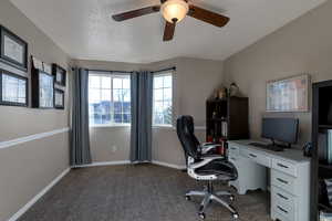 Carpeted office space featuring a ceiling fan and baseboards