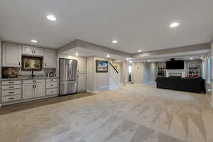 Kitchen featuring open floor plan, freestanding refrigerator, dark carpet, light stone counters, and a fireplace
