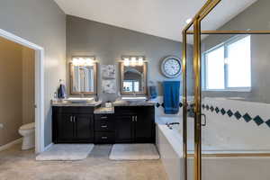 Bathroom with double vanity, a garden tub, vaulted ceiling, and a shower stall