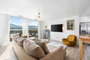 Living room with a textured ceiling, light wood-type flooring, and a wall of windows