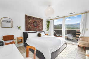 Bedroom with wood finished floors, a mountain view, and access to exterior