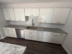 Kitchen with light stone counters, decorative backsplash, and stainless steel dishwasher